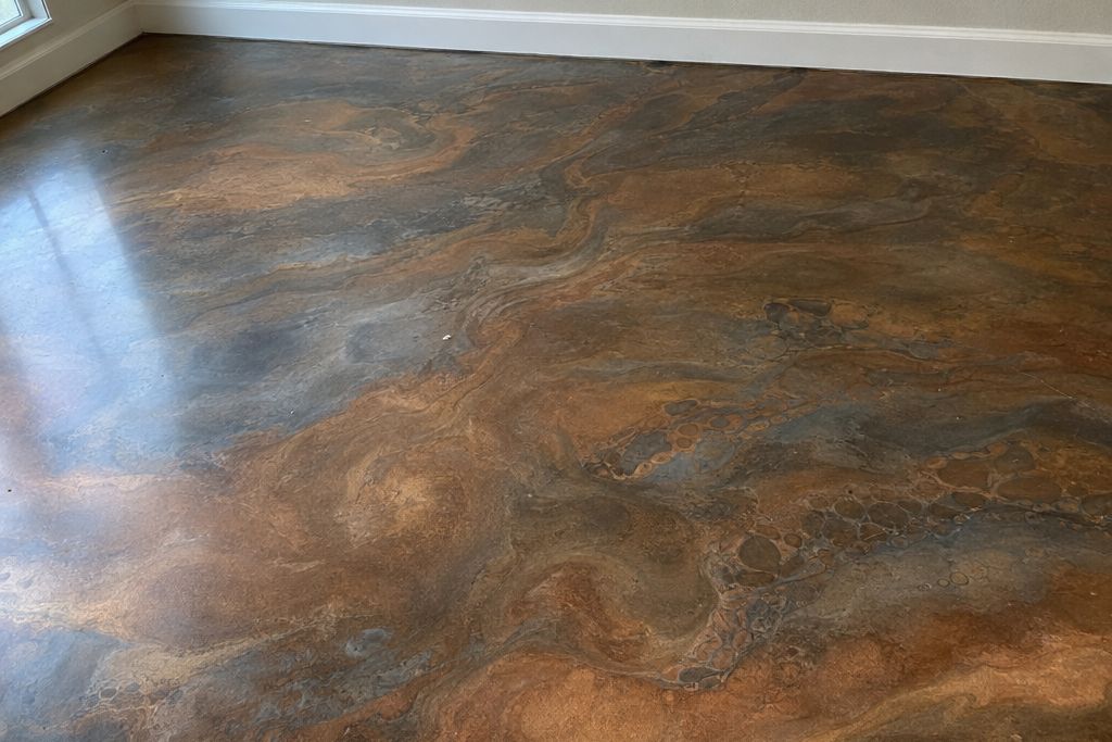 Close view of a bronze and gray metallic epoxy floor showing swirling patterns and soft depth under daylight