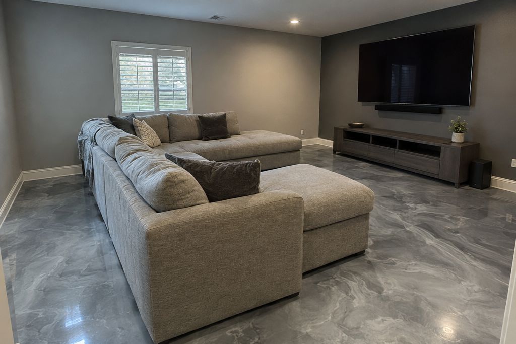 Media room in a newer house with a smoky gray metallic epoxy floor, a sectional and a big screen