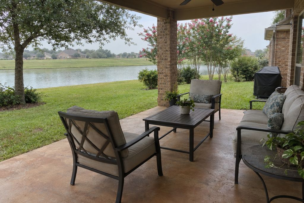 Patio of a newer house with a light brown stained concrete slab near a lake and a levee